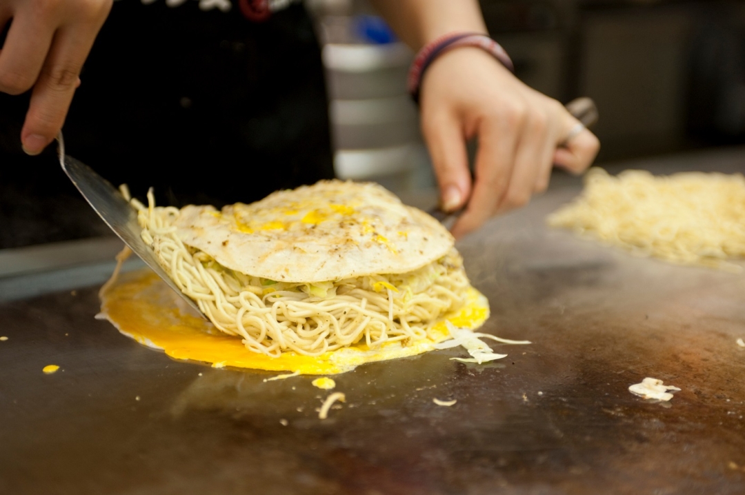 Okonomiyaki being made on an iron plate.